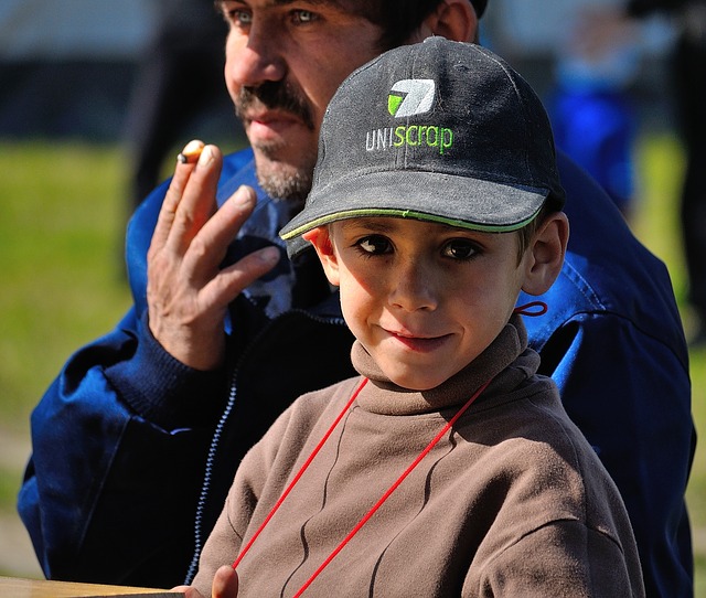 A child with his father smoking in the background.