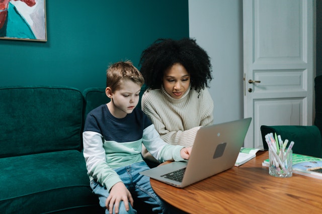 An adult and a child with a laptop.