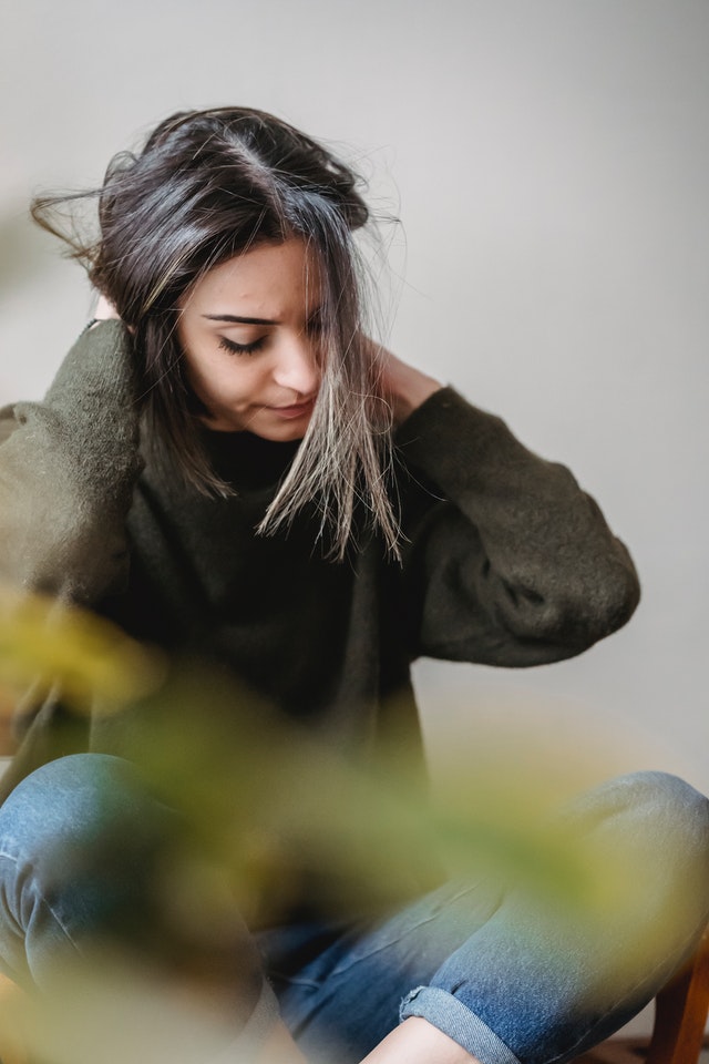 A woman who looks stressed, clutching the back of her head.